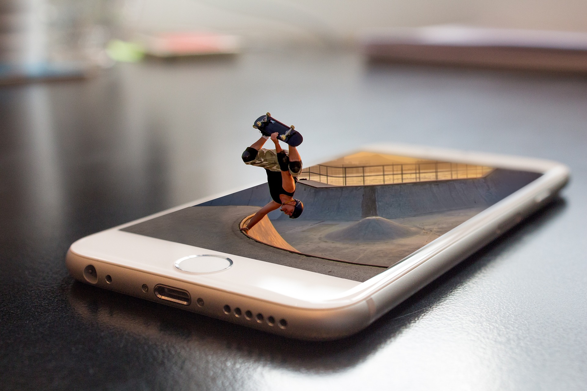 Ein Handy zeigt das Bild einer Rampe. Ein Skateboardfahrer springt aus dem Bild.